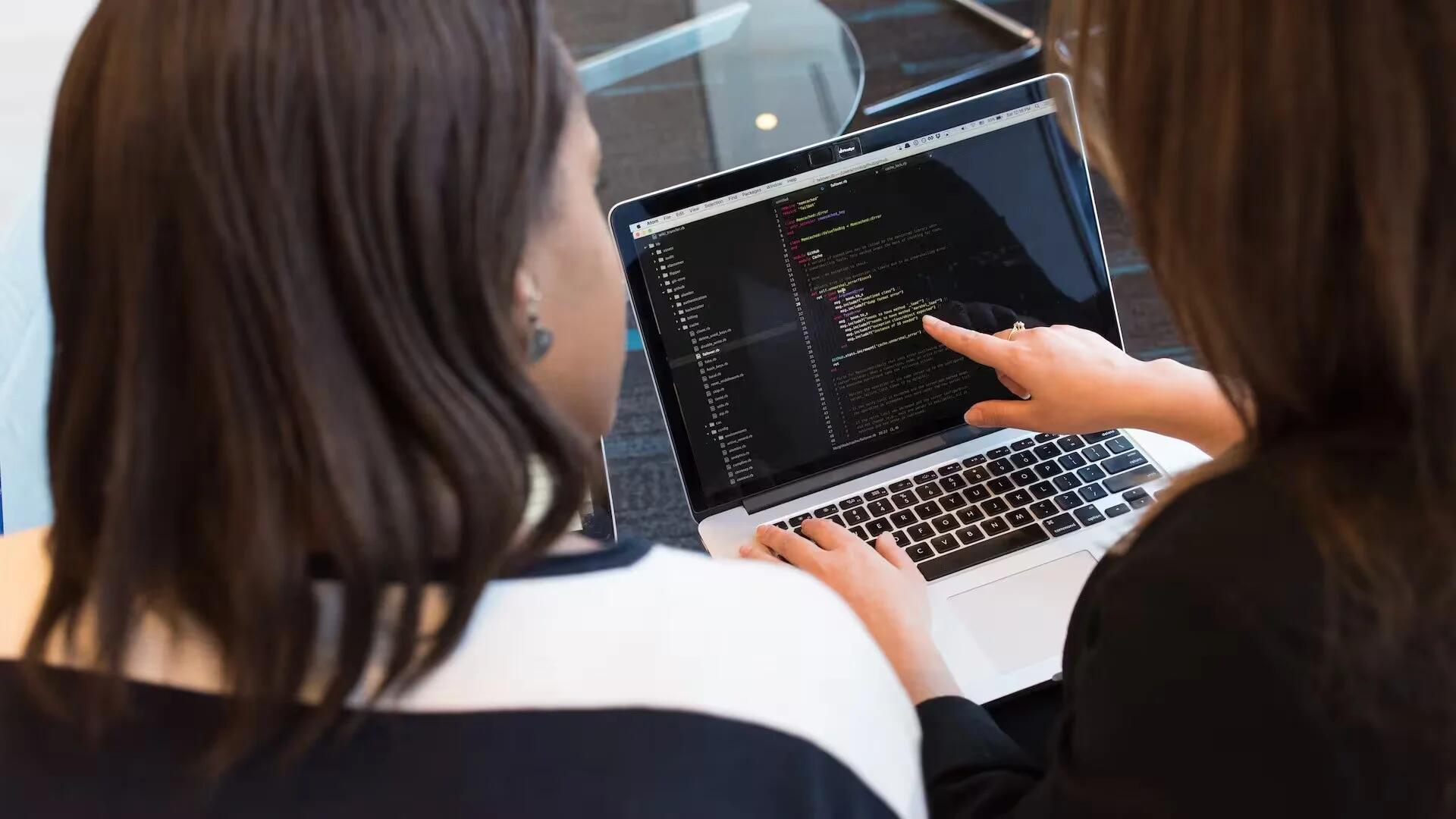 Two Women Looking At Code